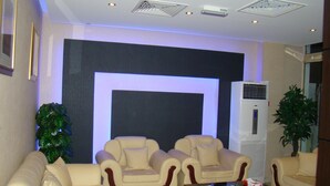 A modern living room with two cream-colored sofas, a coffee table, and a large wall-mounted screen. - Savoy Grand Hotel Apartments (Muscat)
