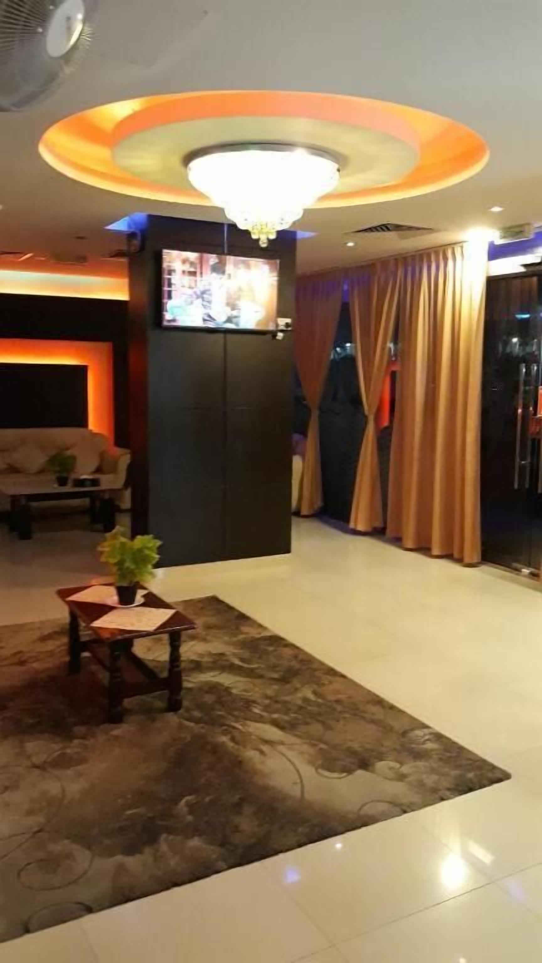Et hotellobby med fjernsyn, lysekrone, sofa og sofabord.