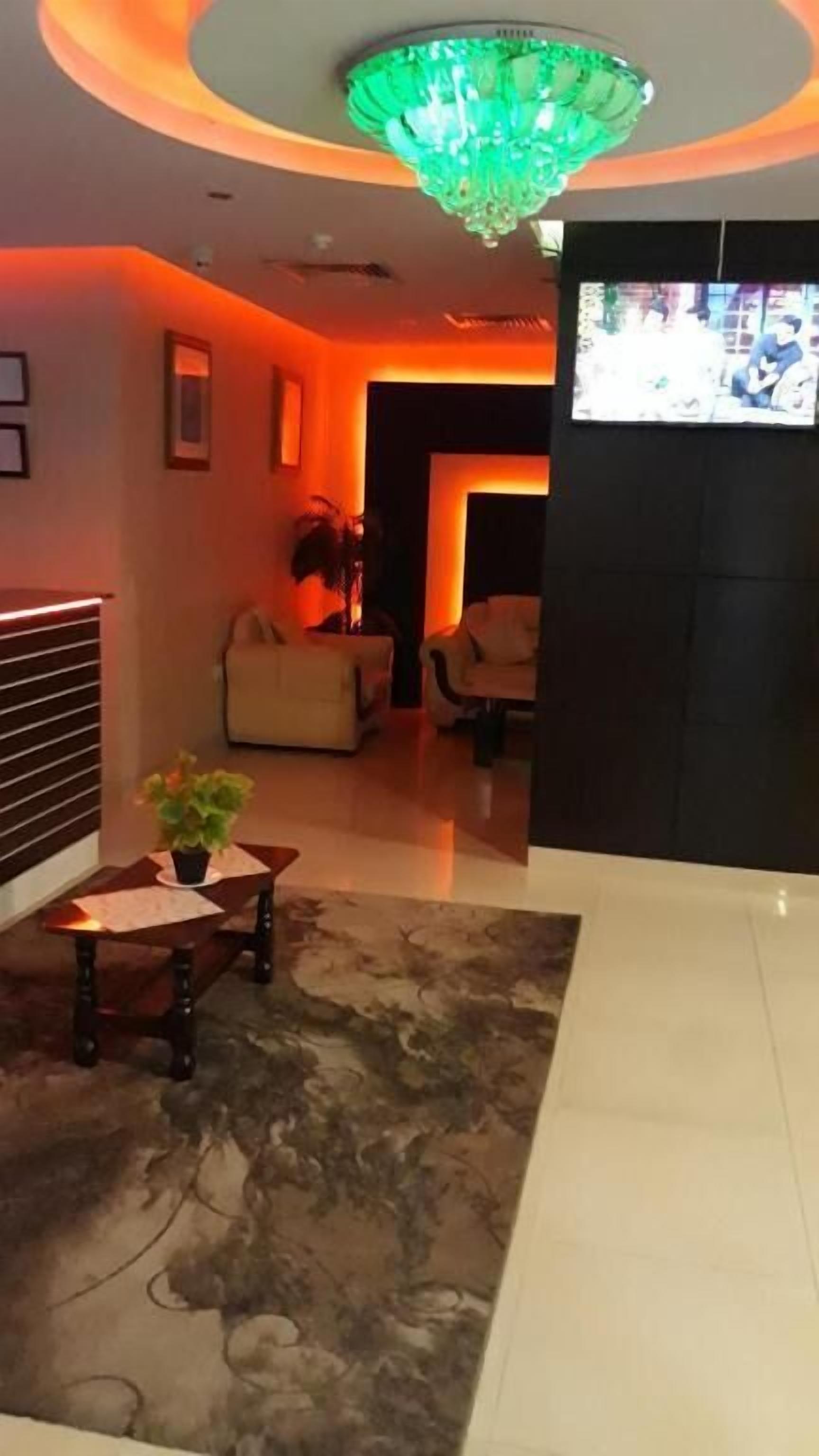 A modern lobby with a chandelier, seating area, and a television screen.