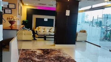 Un vestíbulo de hotel con una araña, una recepción, un sofá y una alfombra grande.