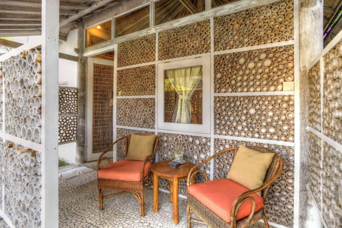 A room with wicker furniture, a tiled floor, and a decorative wall with circular patterns.