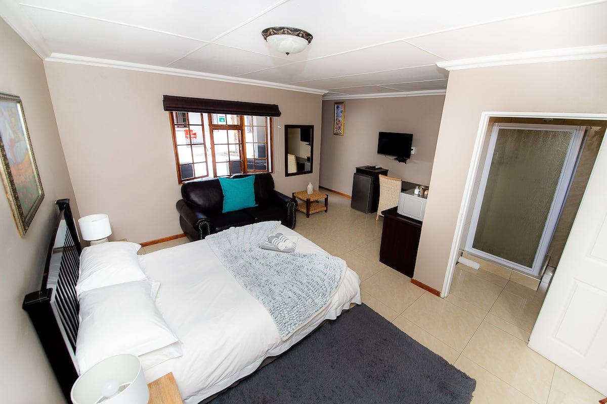 Ein Hotelzimmer mit Bett, Schreibtisch, Stuhl, Fernseher und einem Fenster mit Jalousien.