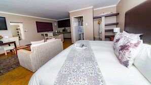 Ein Hotelzimmer mit Bett, einer kleinen Küchenzeile, einer Sitzecke und einem Badezimmer.