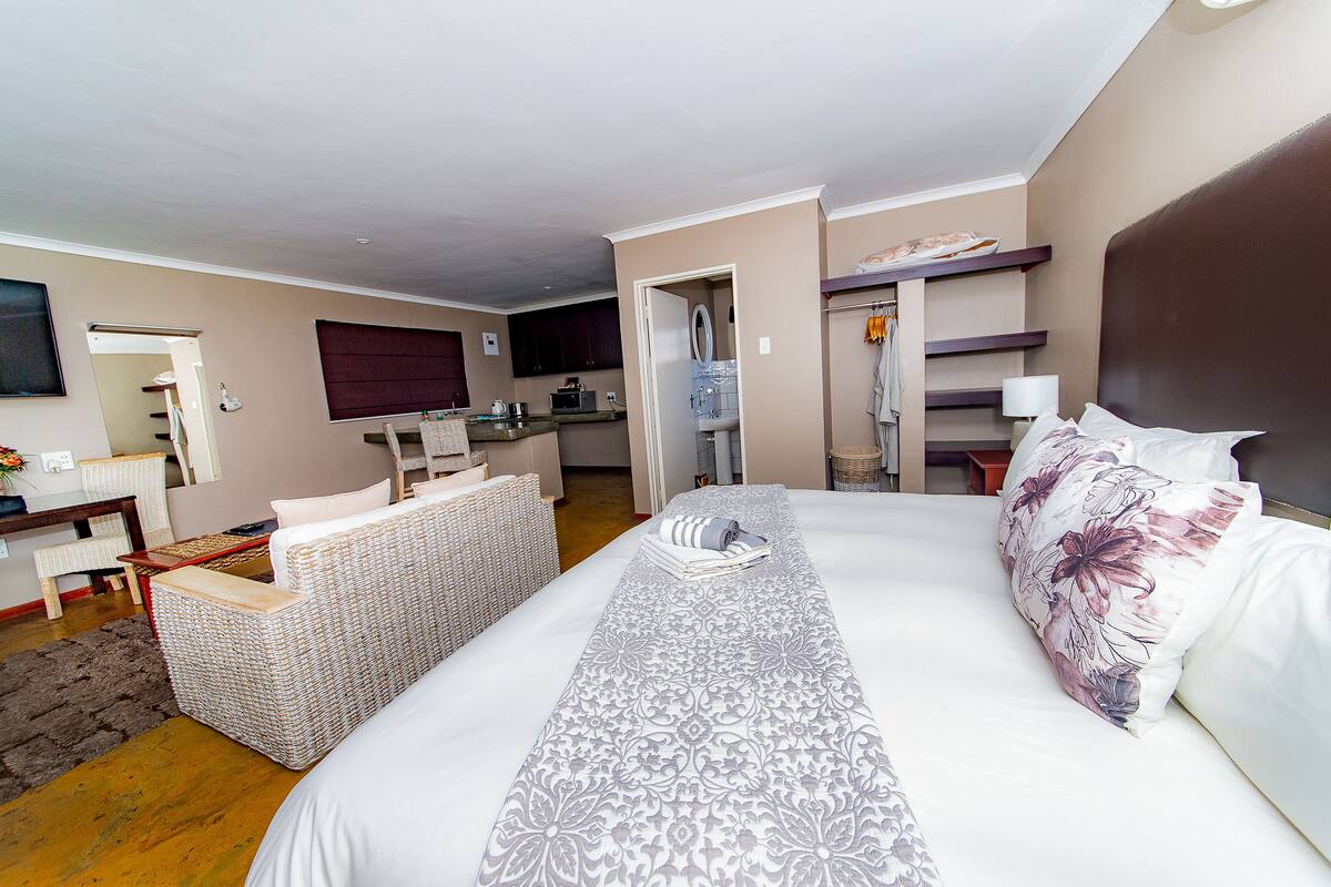 Ein Hotelzimmer mit Bett, einer kleinen Küchenzeile, einer Sitzecke und einem Badezimmer.