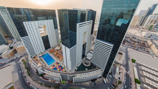 A high-rise building complex with multiple skyscrapers, a central courtyard with a pool, and surrounding roads.