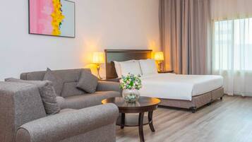 Ein Hotelzimmer mit einem Bett, einem Sofa, einem kleinen Tisch mit einer Vase und einem Bild an der Wand.