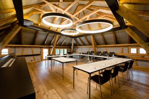 Amplia habitación con techo de madera alto, varias mesas y sillas dispuestas para reuniones.