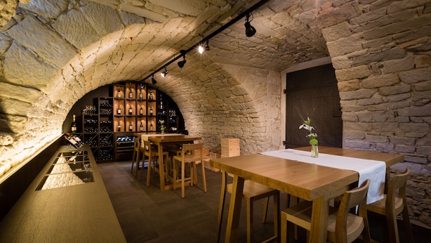 A rustic cellar with stone walls, wooden tables, and a wine rack. - Hotel Krone Speicher (Speicher)