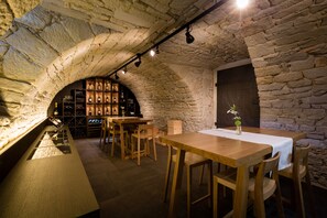 A rustic cellar with stone walls, wooden tables, and a wine rack. - Hotel Krone Speicher (Speicher)