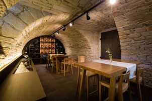 Una bodega rústica con paredes de piedra, mesas de madera y un botellero.
