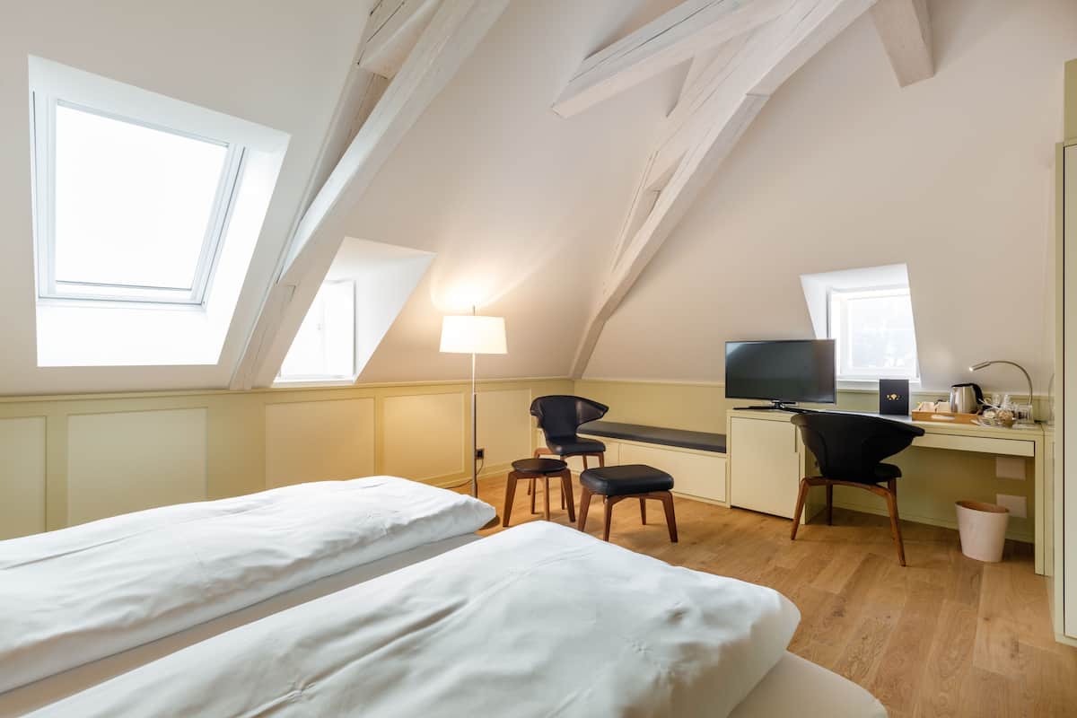 Une chambre avec deux lits, un bureau, une chaise, une télévision et une fenêtre.