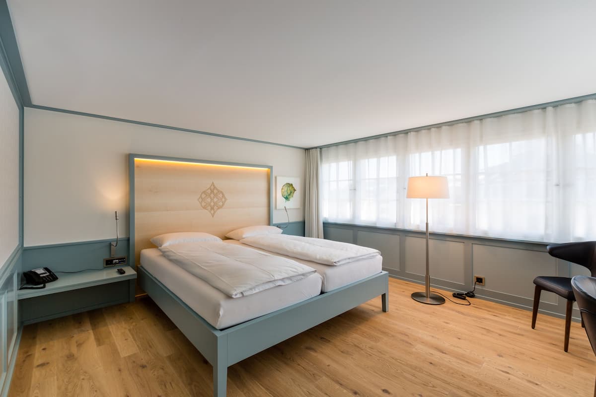 Une chambre d’hôtel moderne équipée d’un lit double, d’une table de chevet avec une lampe et d’une chaise.