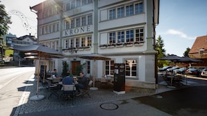A building with the name "KRONE" on the facade, outdoor seating with umbrellas, and a cobblestone street. - Hotel Krone Speicher (Speicher)