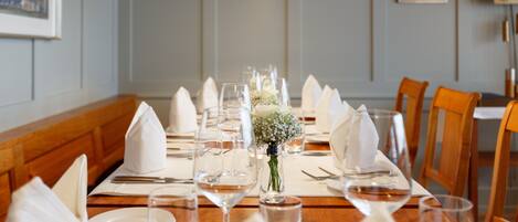 Una mesa de comedor dispuesta con servilletas blancas, copas de vino y un pequeño florero con flores.