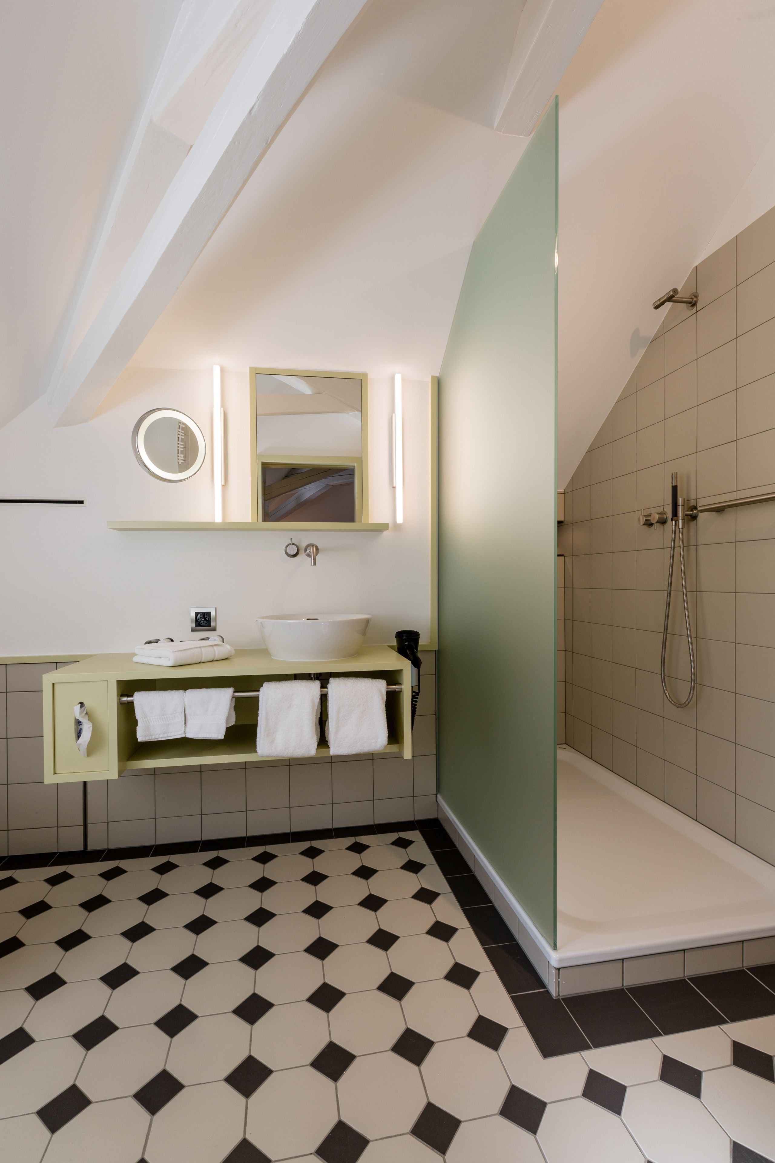 Un baño moderno con un lavamanos blanco, un espejo y una ducha.