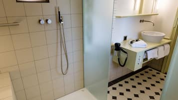 A modern bathroom with a glass shower enclosure, a white sink, and a tiled floor.