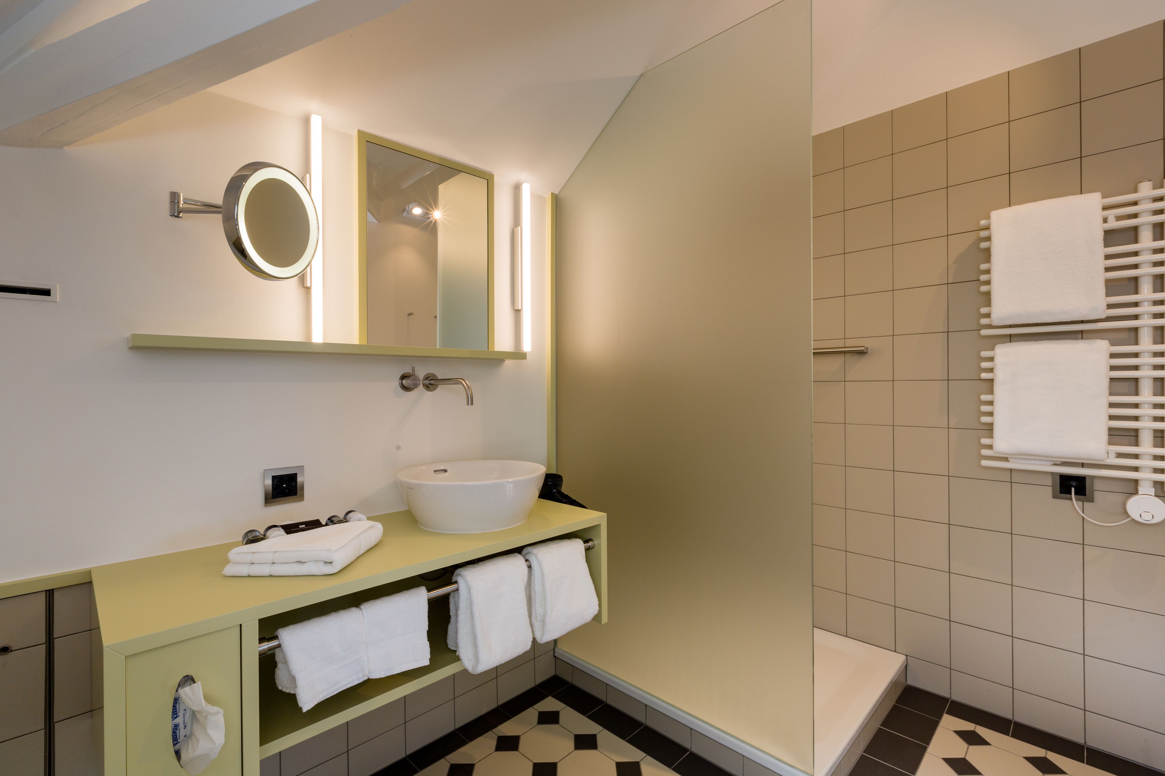 A modern bathroom with a sink, mirror, and towel rack.
