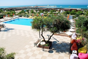 A pool area with lounge chairs, a table, and a tree. - Monachus Hotel & Spa - All Inclusive (Manavgat)