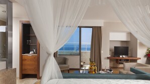 A hotel room with a large bed, a television, a seating area, and a view of the ocean. - Commodore Elite Suites & Spa - All Inclusive - Adult Only (Manavgat)