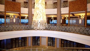 A multi-level hotel lobby with a central chandelier, glass railings, and a view of the cityscape. - Commodore Elite Suites & Spa - All Inclusive - Adult Only (Manavgat)