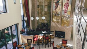 Un comedor amplio con techos altos, una barra central y vistas al exterior.