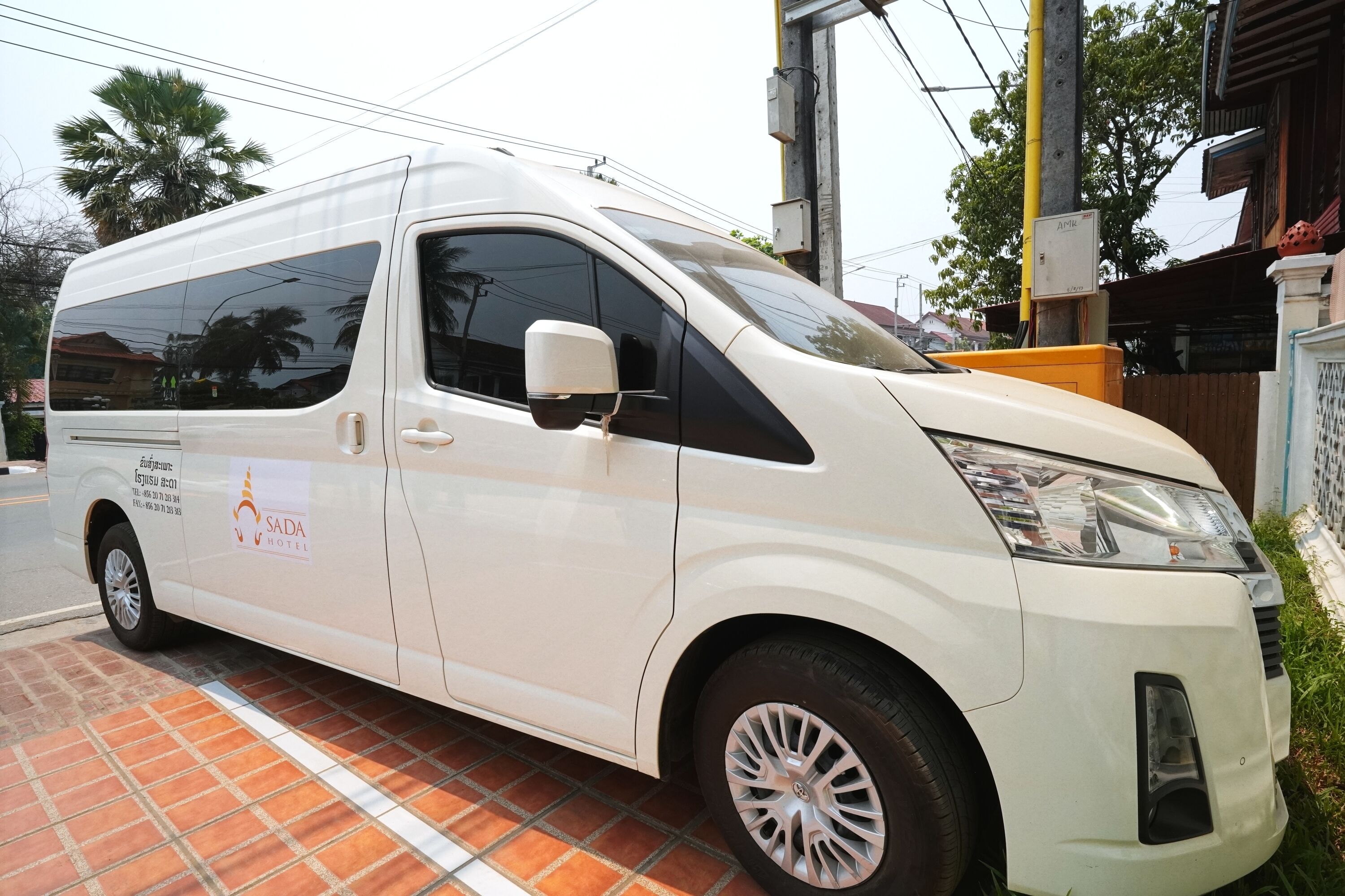 A white van parked on a tiled surface with a logo and contact information on its side.
