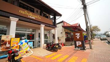A 7-Eleven convenience store with a parking sign, a motorcycle, and a pedestrian crossing.