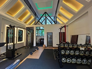 A gym with exercise equipment, weight racks, and a skylight ceiling. - Sada Hotel (Luang Prabang)