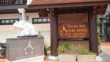A hotel entrance with a signboard displaying the name 'SADA HOTEL' and contact information.