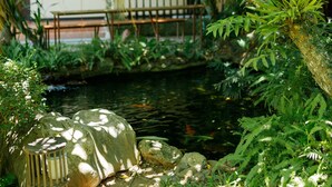 A serene garden with a pond, a wooden bench, and lush greenery. - Sada Hotel (Luang Prabang)