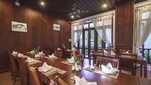 A dining area with wooden tables, chairs, and a ceiling fan. - Sada Hotel (Luang Prabang)