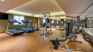 Un gimnasio con cintas de correr, máquinas de pesas y un espejo grande.