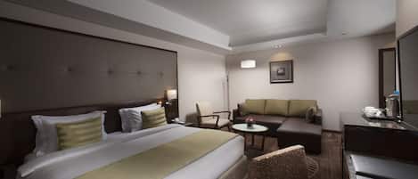 Una habitación de hotel con una cama grande, un sofá, un escritorio y una silla.