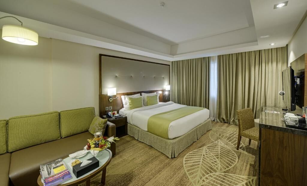 Une chambre d’hôtel avec un grand lit, un canapé, un bureau et un miroir.