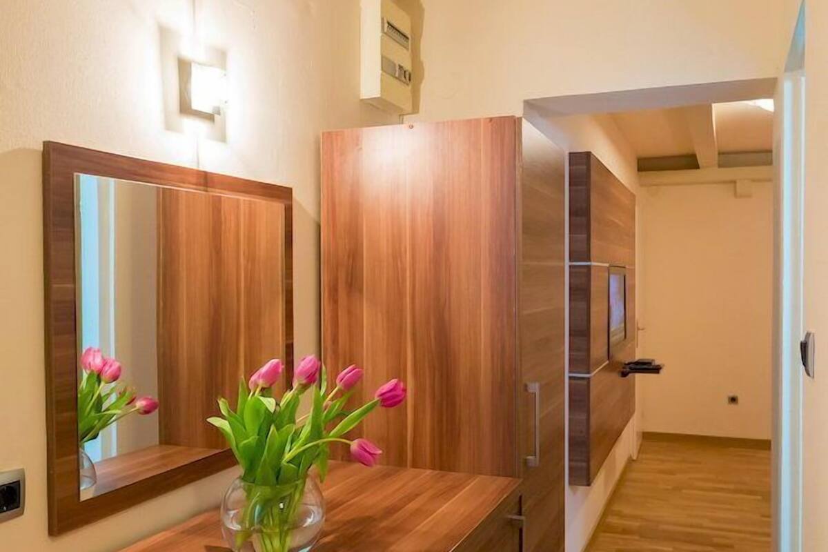 A modern kitchen with wooden cabinets, a built-in oven, and a bright light fixture above the counter.