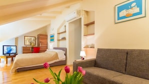 Una camera da letto moderna con un letto, un divano, una TV e un vaso di tulipani.