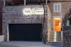 A stone facade with a sign reading "Villa Dorma" and a dark garage door. - Villa Dorma (Dubrovnik)