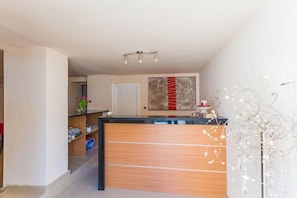 A modern kitchen with a wooden counter, a white door, and a red abstract painting on the wall. - Villa Dorma (Dubrovnik)