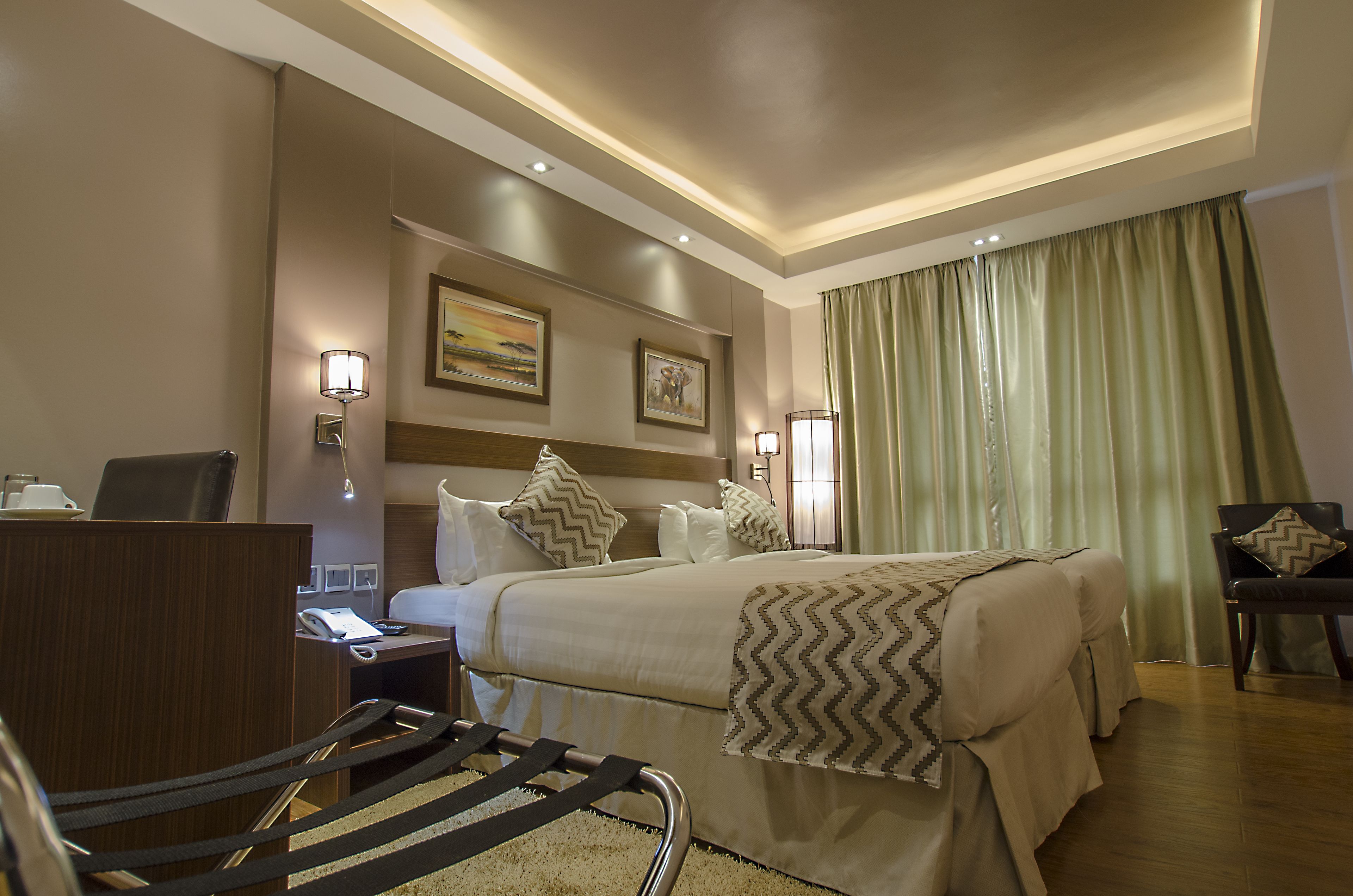 Una habitación de hotel con cama, escritorio, silla y cortinas.