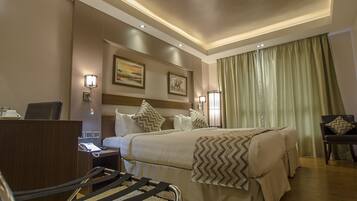 Una habitación de hotel con cama, escritorio, silla y cortinas.