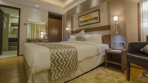 Habitación de hotel con una cama grande, una mesita de noche, una lámpara, un espejo y un cuadro en la pared.