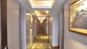 Un pasillo de hotel con piso alfombrado, obras de arte enmarcadas en las paredes e iluminación empotrada.