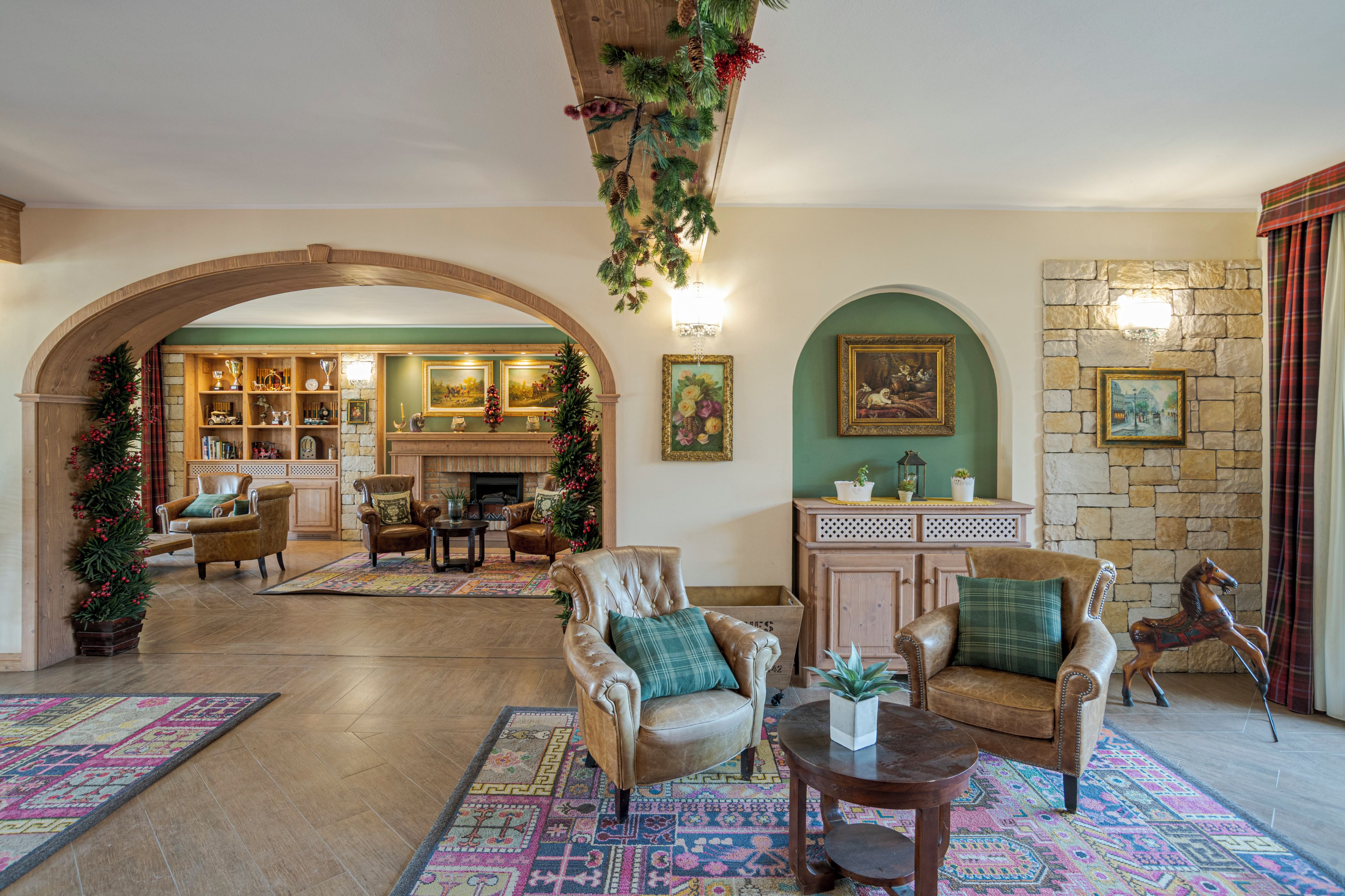 A spacious lobby with a fireplace, leather armchairs, a coffee table, and a stone wall with framed artwork.