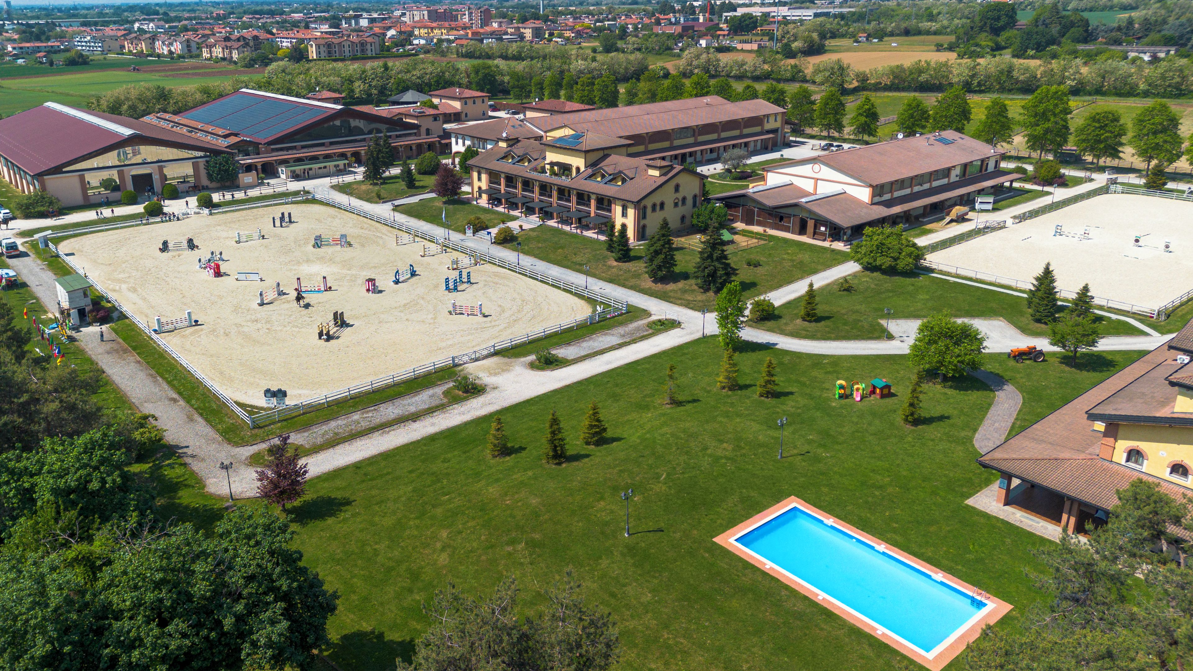 An equestrian facility with a large indoor arena, outdoor riding areas, and a swimming pool.
