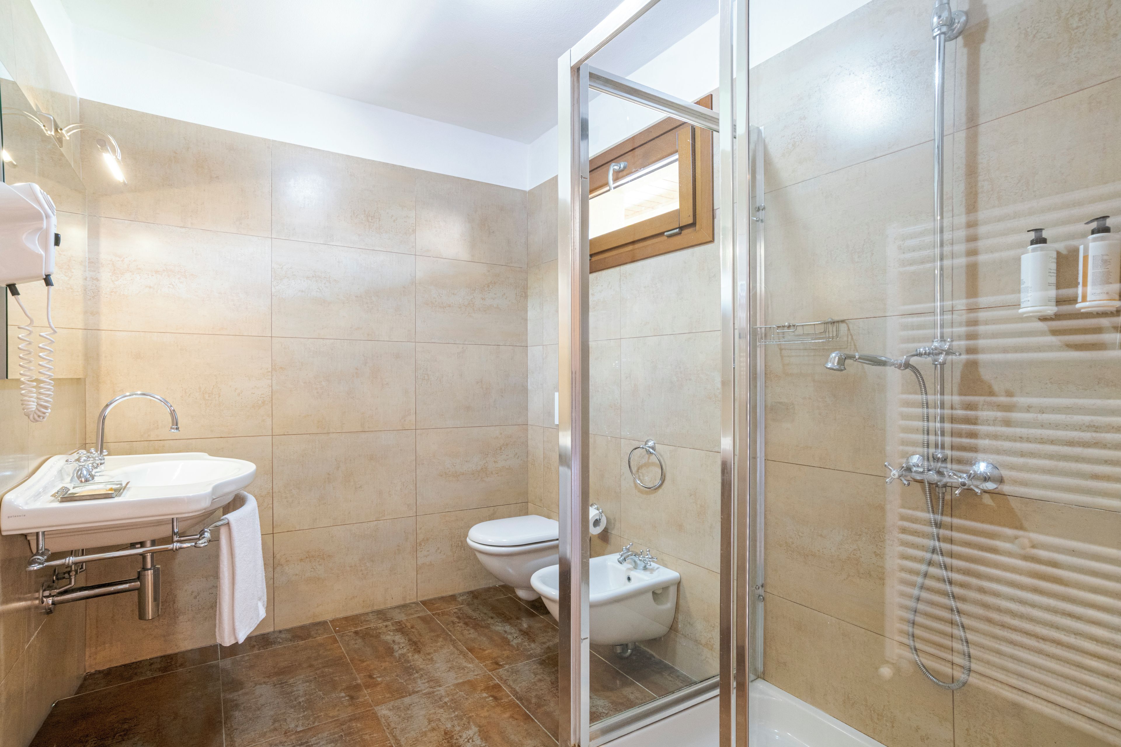 Une salle de bain avec une douche à parois de verre, un lavabo avec un porte-serviettes et des toilettes.