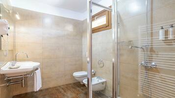 Une salle de bain avec une douche à parois de verre, un lavabo avec un porte-serviettes et des toilettes.
