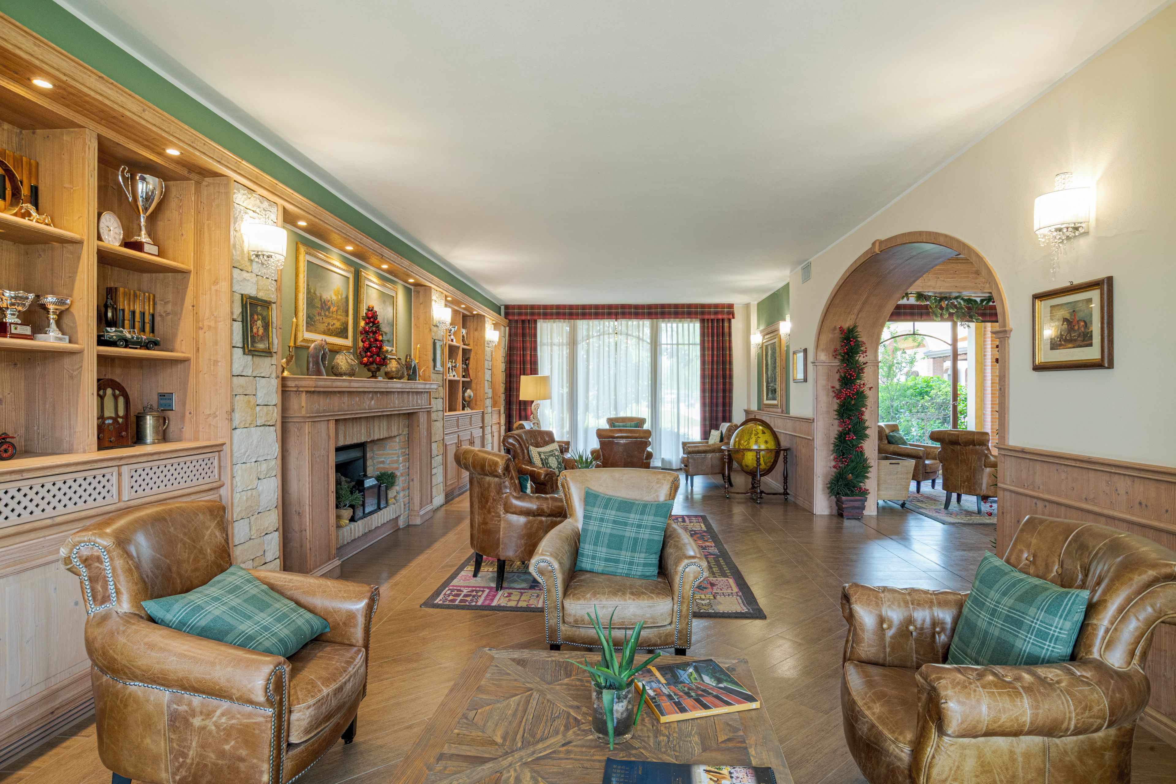 A spacious living room with leather armchairs, a fireplace, and a variety of decorative items on shelves.