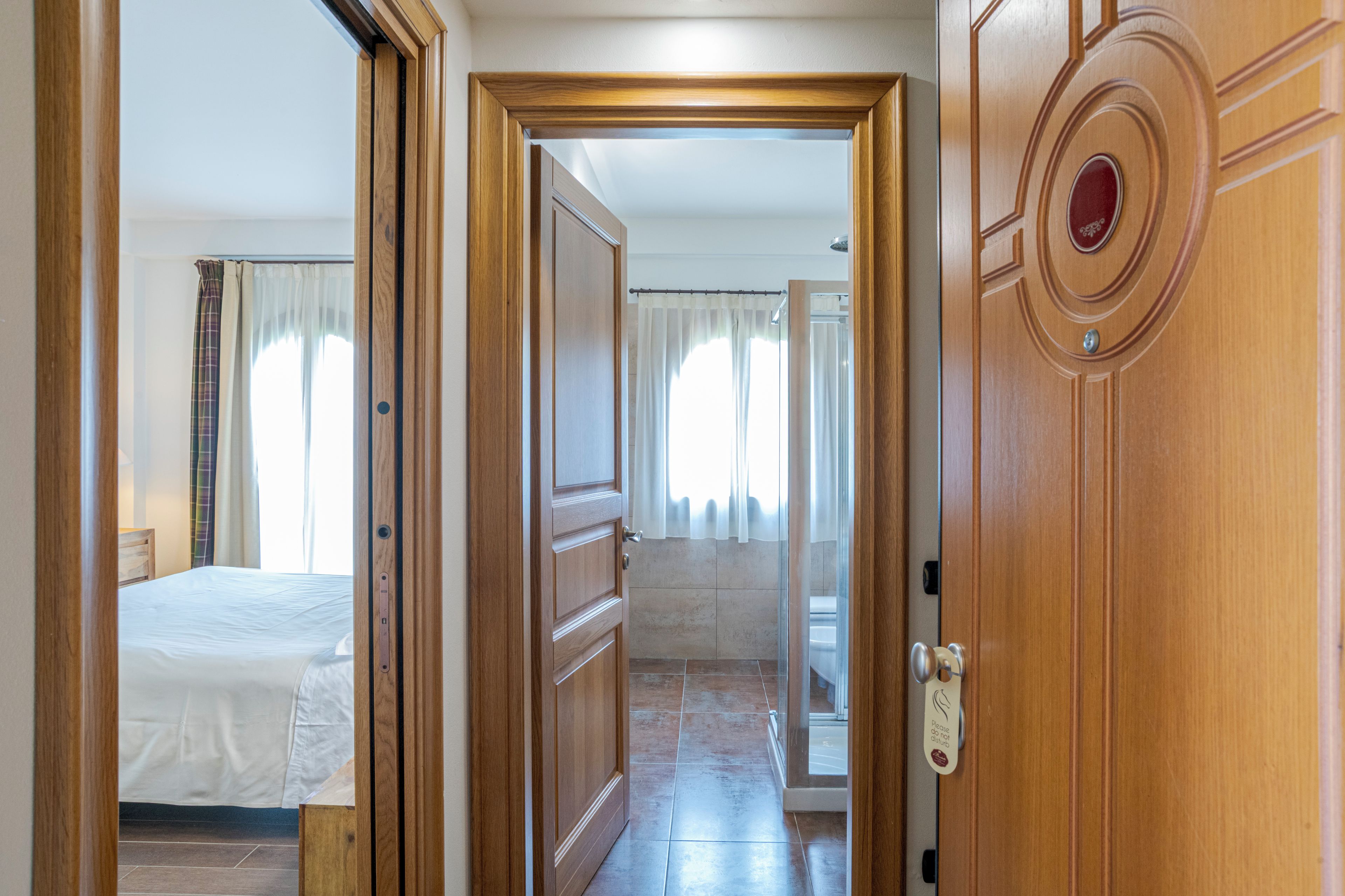 Ein Hotelzimmer mit einem Bett, einem Badezimmer und einem Flur, der in ein weiteres Zimmer führt.