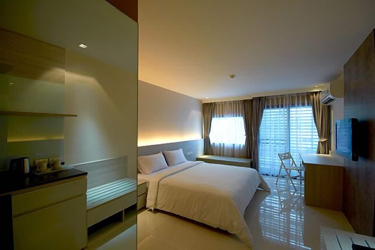 Ein modernes Hotelzimmer mit einem großen Bett, Nachttischen, einem Schreibtisch und einem Fernseher.