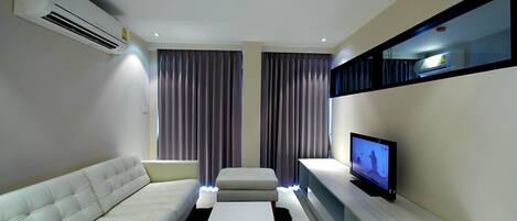 Een moderne woonkamer met een bank, een flatscreen televisie en een inbouwkast.